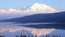 Lumen peittämä vuori ja erämaajärvi Alaskassa.